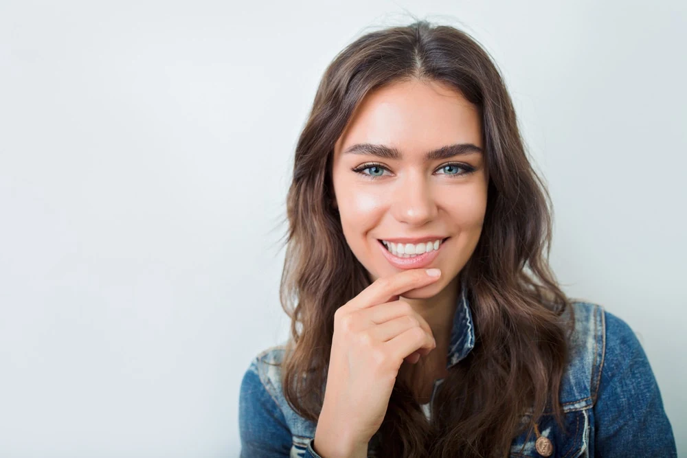 A smiling brunette woman wearing a denim jacket