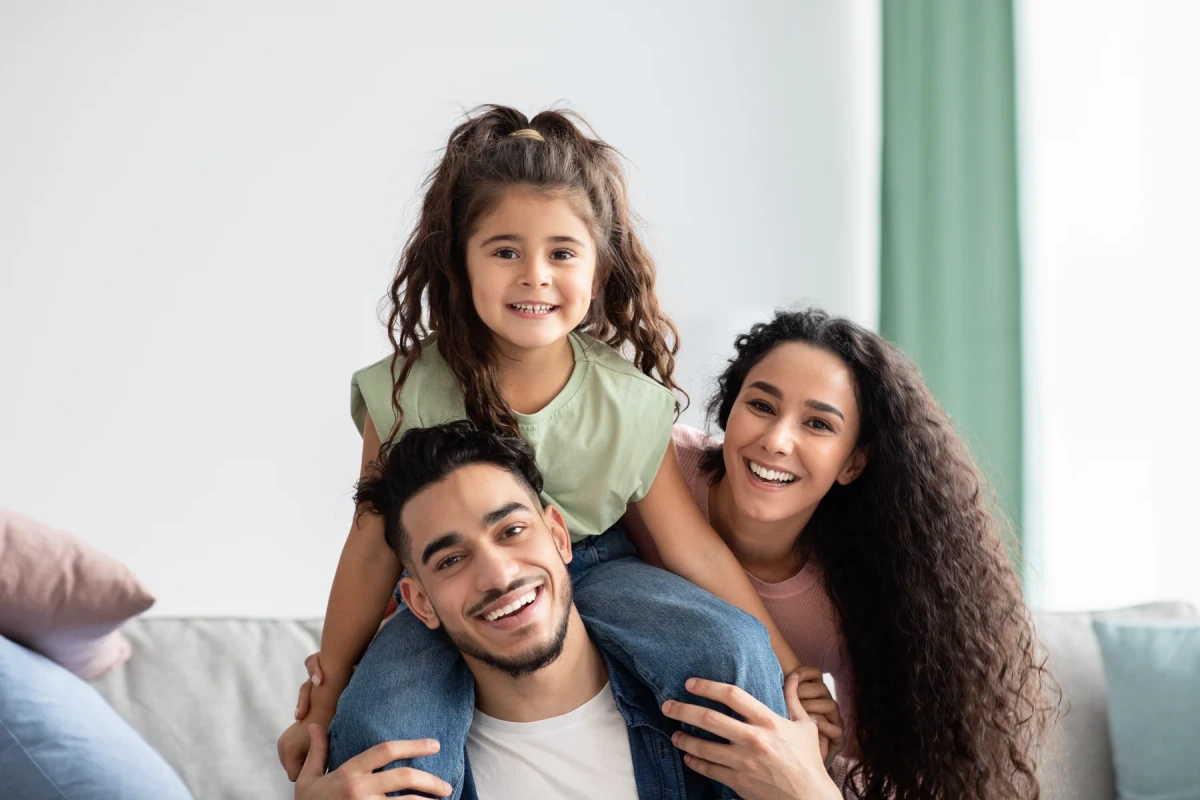 Smiling parents with their daughter on her father’s shoulders