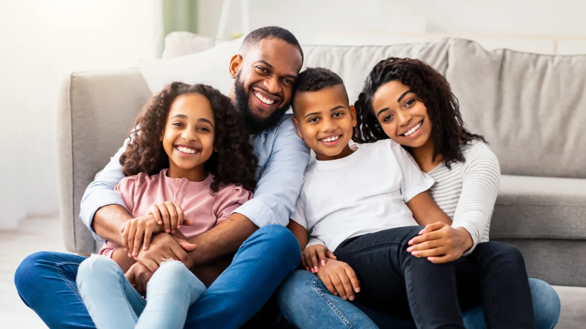 Two parents and their two children smiling together at home